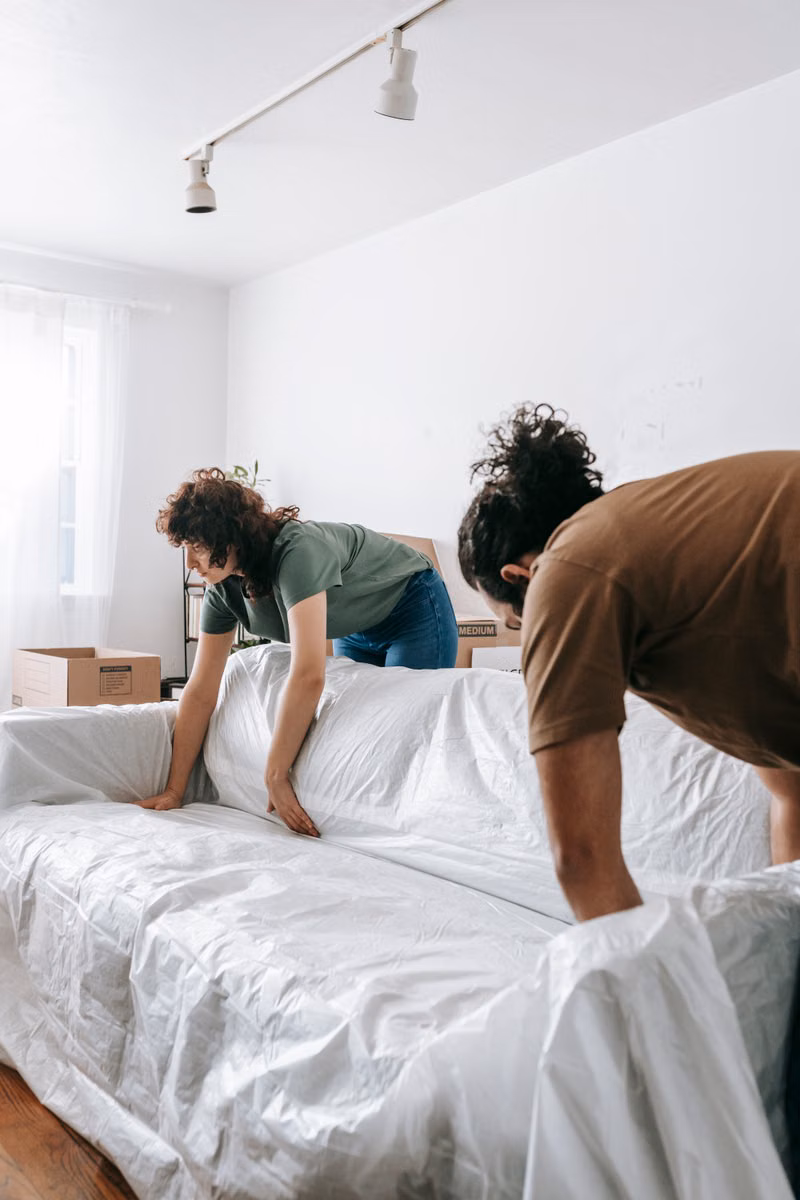 Movers placing protected furniture inside a new Phoenix home